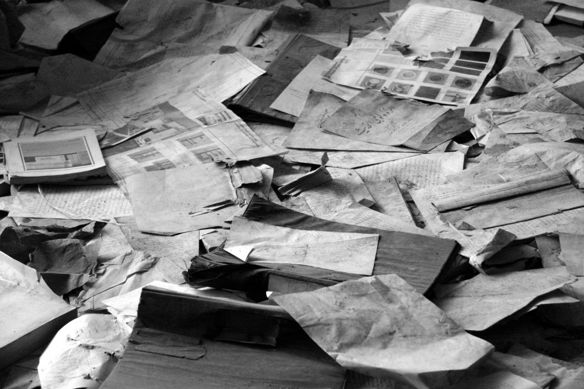 Black and white photograph of old newspapers strewn across the floor